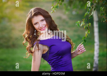 junge Frau im lila Kleid Wandern im Sommerpark Stockfoto