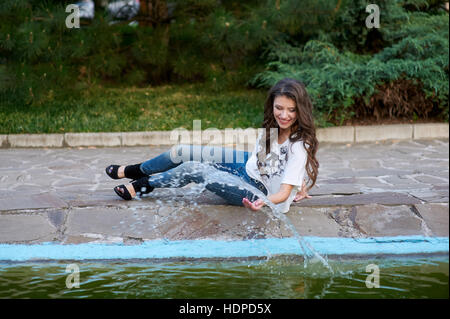 schöne Frau sitzt in der Nähe der Brunnen im Park Stockfoto