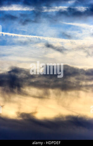 Dunkle Wolken am Himmel bei Sonnenuntergang mit dem Flugzeug Kondensstreifen Stockfoto