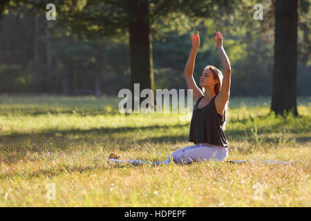 Junge Frau praktiziert Yoga im park Stockfoto