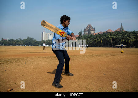 Ein indischer Mann spielt Cricket in zentralen Mumbai in seiner Mittagspause. Stockfoto