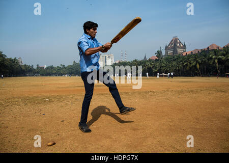 Ein indischer Mann spielt Cricket in zentralen Mumbai in seiner Mittagspause. Stockfoto