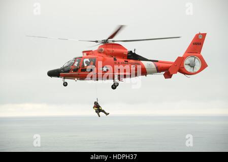 Ein US-Küstenwache Pararescue Offizier baumelt aus einem Eurocopter MH-65 Dolphin-Suche und Rettung Hubschrauber während einer Advanced Helikopter Rettung School-Übung in der Nähe von North Head Lighthouse 10. November 2016 in Ilwaco, Washington. Stockfoto