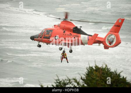 Ein US-Küstenwache Pararescue Offizier wird von einem Eurocopter MH-65 Dolphin-Suche und Rettung Hubschrauber während einer Advanced Helikopter Rettung School-Übung in der Nähe von North Head Lighthouse 10. November 2016 in Ilwaco, Washington abgesenkt. Stockfoto