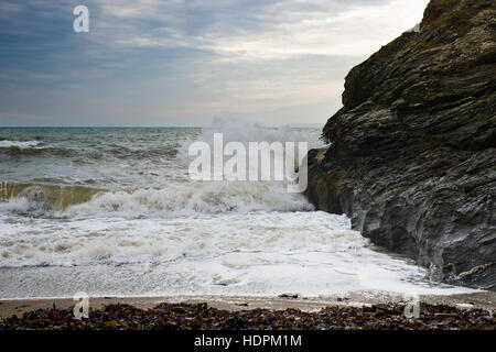 Tosende Wellen gegen die Felsen in einer isolierten Nische entlang der South West Coastal Path, Cornwall, UK Stockfoto