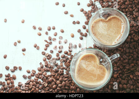 Herzförmige Kaffeetassen auf hölzernen Hintergrund mit Kaffeebohnen Stockfoto