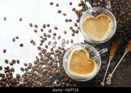 Herzförmige Kaffeetassen auf hölzernen Hintergrund mit Kaffeebohnen Stockfoto