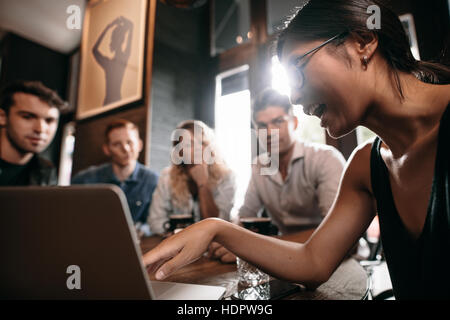 Junge Frau auf Laptop zeigen und diskutieren mit Freunden. Gruppe von Jugendlichen im Café Blick auf Laptop-Computer.
