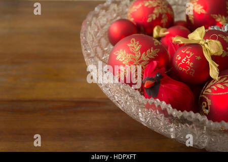 Eine realistische Kardinal Dekoration und dekorative Weihnachtskugeln in eine Kristallschale mit den Worten "Joy to the World." Fotografiert von der Seite. Stockfoto
