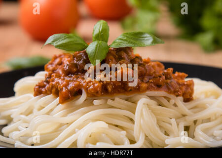 Spaghetti Bolognese mit Basilikum Blätter auf schwarzem Teller Stockfoto