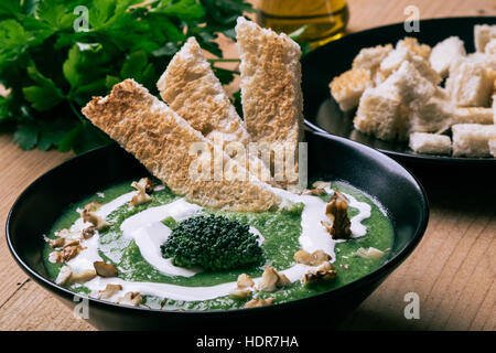 Hausgemachte grüne Creme Brokkolisuppe in schwarz Schüssel Stockfoto