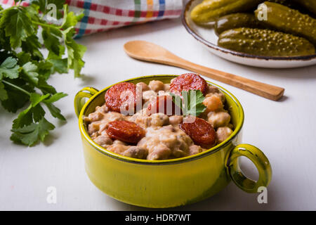 Bohnen-Eintopf mit Würstchen in grüner Schale Stockfoto