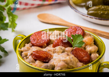 Bohnen-Eintopf mit Würstchen in grüner Schale Stockfoto