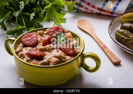 Bohnen-Eintopf mit Würstchen in grüner Schale Stockfoto