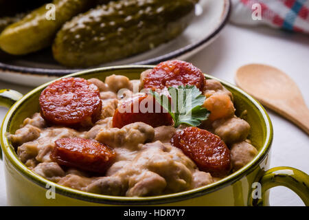 Bohnen-Eintopf mit Würstchen in grüner Schale Stockfoto