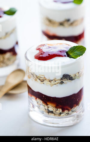 gesunde Joghurt-Parfait mit Marmelade im Glas auf weißen Tisch Stockfoto