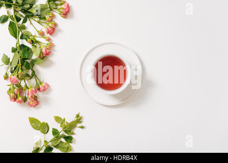 Zweig der Rosen liegt in der Nähe der Teetasse Stockfoto