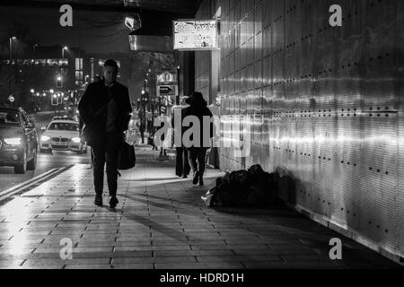 Obdachloser schläft rau, während Leute in Leeds, West Yorkshire, England vorbeigehen Stockfoto