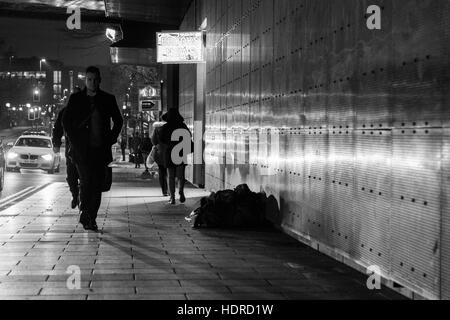 Obdachloser schläft rau, während Leute in Leeds, West Yorkshire, England vorbeigehen Stockfoto