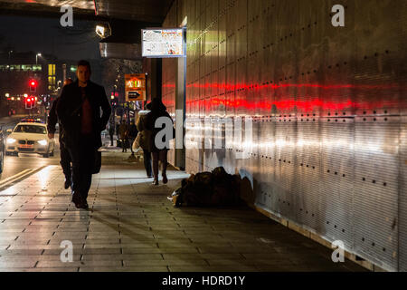 Obdachloser schläft rau, während Leute in Leeds, West Yorkshire, England vorbeigehen Stockfoto