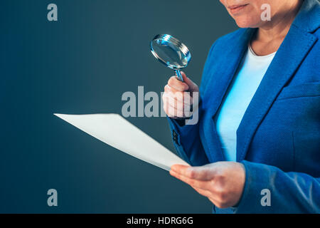 Weibliche Steuerinspektor Blick auf finanzielle Unternehmensdokumente mit Lupe Stockfoto