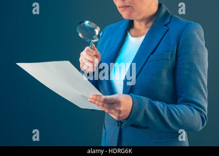 Weibliche Steuerinspektor Blick auf finanzielle Unternehmensdokumente mit Lupe Stockfoto