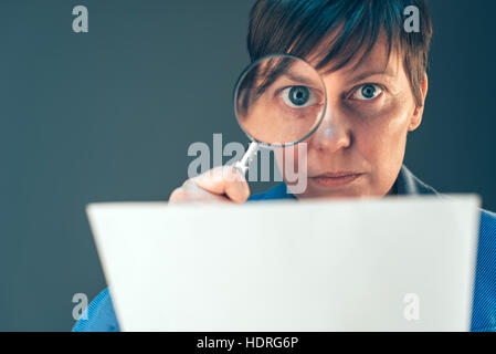 Weibliche Steuerinspektor Blick auf finanzielle Unternehmensdokumente mit Lupe Stockfoto