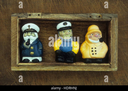 Holzkiste mit Modellen der drei Seeleute verkleidet als Kapitän oder Fischer jeder raucht eine Pfeife Stockfoto