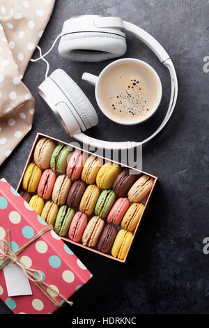 Bunte Macarons in einer Geschenkbox und Kopfhörer am Steintisch. Süßen Macarons. Ansicht von oben Stockfoto