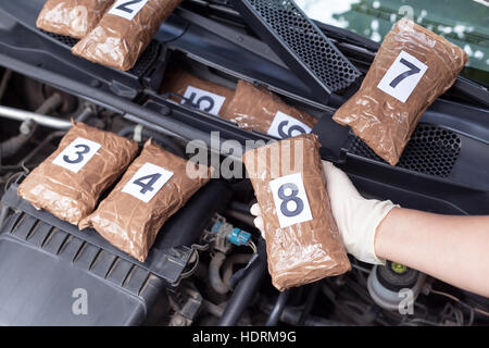 Polizist Medikament Paket entdeckt im Motorraum eines Autos Stockfoto