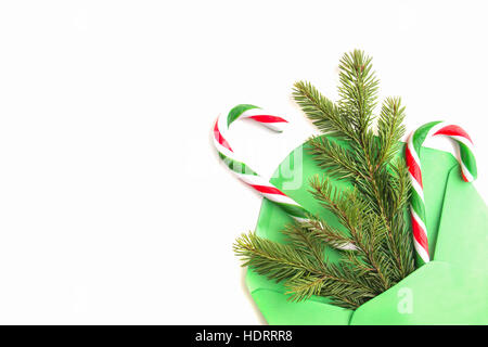 Cristmas Zusammensetzung. Grünen Umschlag, Fir tree Branch und Candy Canes auf weißem Hintergrund. Ansicht von oben. Flach zu legen Stockfoto