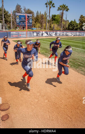 Gemischtrassig Studentinnen Softball Spieler sprinten Vorbereitung auf ein Spiel auf dem Feld in Fullerton, Kalifornien. Stockfoto