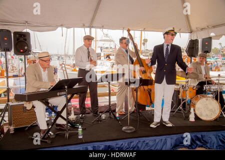 Seine Sänger in einer Yachting Kappe geschmückt, unterhält eine Band Besuchern einer Ausstellung von Oldtimer Holzbooten in einer Marina in Newport Beach, Kalifornien. Stockfoto