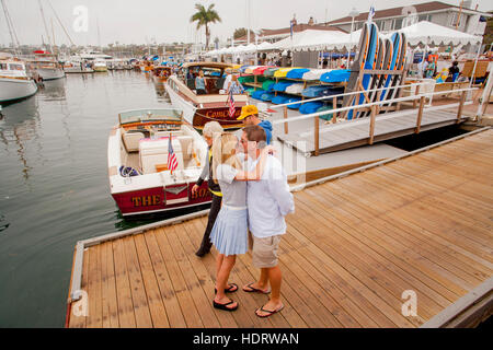 Ein paar knutschen auf einem Marina Pier während einer Ausstellung von Oldtimer Holzbooten in Newport Beach, Kalifornien. Stockfoto