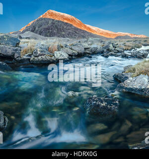 Mountain Creek und Schnee bestäubt Gipfel in Nord-Wales Stockfoto