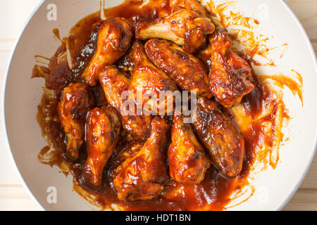 Hühnerflügel Backen auf einer keramischen Pfanne in Soße Stockfoto