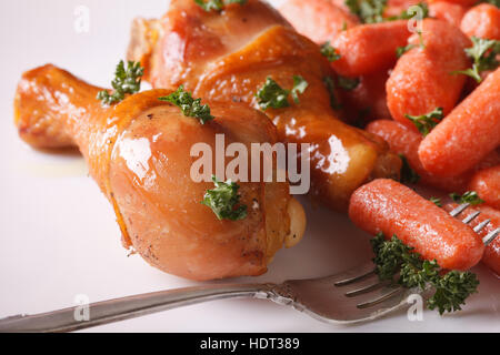 Gegrillte Hähnchenschenkel und karamellisierter Baby-Karotten auf einer Platte Nahaufnahme. horizontale Stockfoto