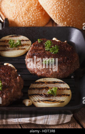 gegrillte Burger mit Zwiebeln und Knoblauch auf dem Grill in der Nähe. vertikale Stockfoto