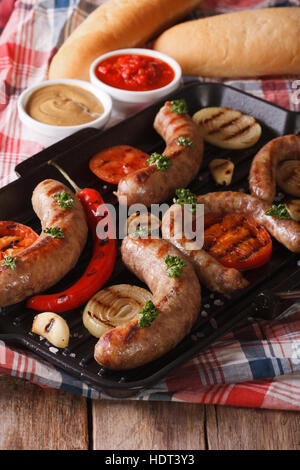 Wurst mit gegrilltem Gemüse und Brötchen mit Sauce auf den Tisch. vertikale Stockfoto