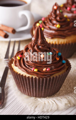 Cupcakes mit Schokocreme close-up und Kaffee auf dem Tisch. vertikale Stockfoto