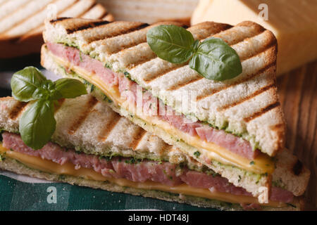 Gegrilltes Sandwich mit Schinken, Käse und Basilikum Nahaufnahme auf dem Tisch. horizontale Stockfoto