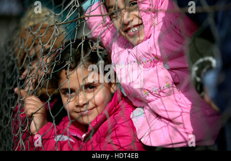 Syrische Flüchtlingskinder peep durch die Umzäunung von einem alten ehemaligen Basketballplatz, die jetzt ihren Schulhof in einem Flüchtlingslager in der Nähe von Taalabaya im Bekaa-Tal. Stockfoto