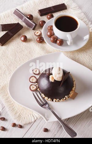 Schokoladenkuchen mit Nüssen auf einem Teller und Kaffee auf dem Tisch. vertikale Ansicht von oben Stockfoto