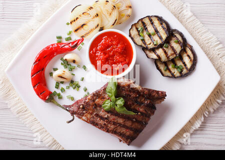 appetitlich Rindersteak, gegrilltes Gemüse und Sauce auf einem Teller. horizontale Ansicht von oben Stockfoto