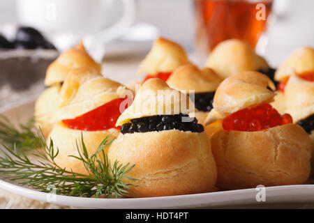 Leckerer Snack: Profiteroles gefüllt mit roten und schwarzen Kaviar auf eine Platte Nahaufnahme. horizontale Stockfoto