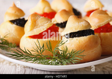 Fingerfood: Profiteroles gefüllt mit roten und schwarzen Kaviar auf eine Platte Nahaufnahme. horizontale Stockfoto