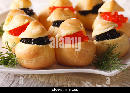Leckere Windbeutel gefüllt mit roten und schwarzen Kaviar auf eine Platte Nahaufnahme. horizontale Stockfoto