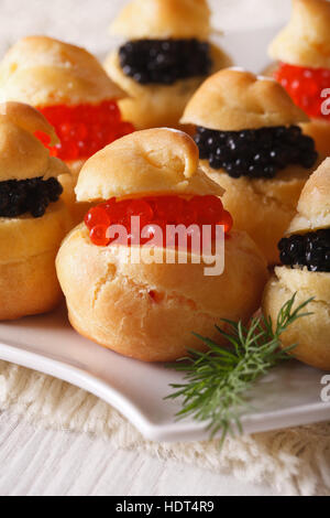 Leckere Windbeutel gefüllt mit roten und schwarzen Kaviar auf eine Platte Nahaufnahme. vertikale Stockfoto