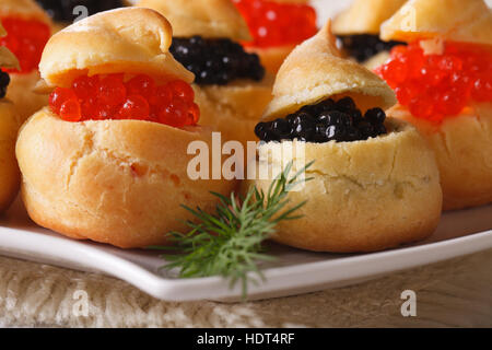 Frischen Windbeutel mit roten und schwarzen Kaviar auf einem Teller-Makro. horizontale Stockfoto