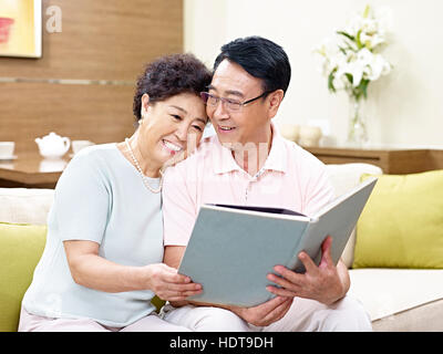 Senior asiatischen paar sitzt auf einem Buch zusammen, glücklich und lächelnd couch Stockfoto